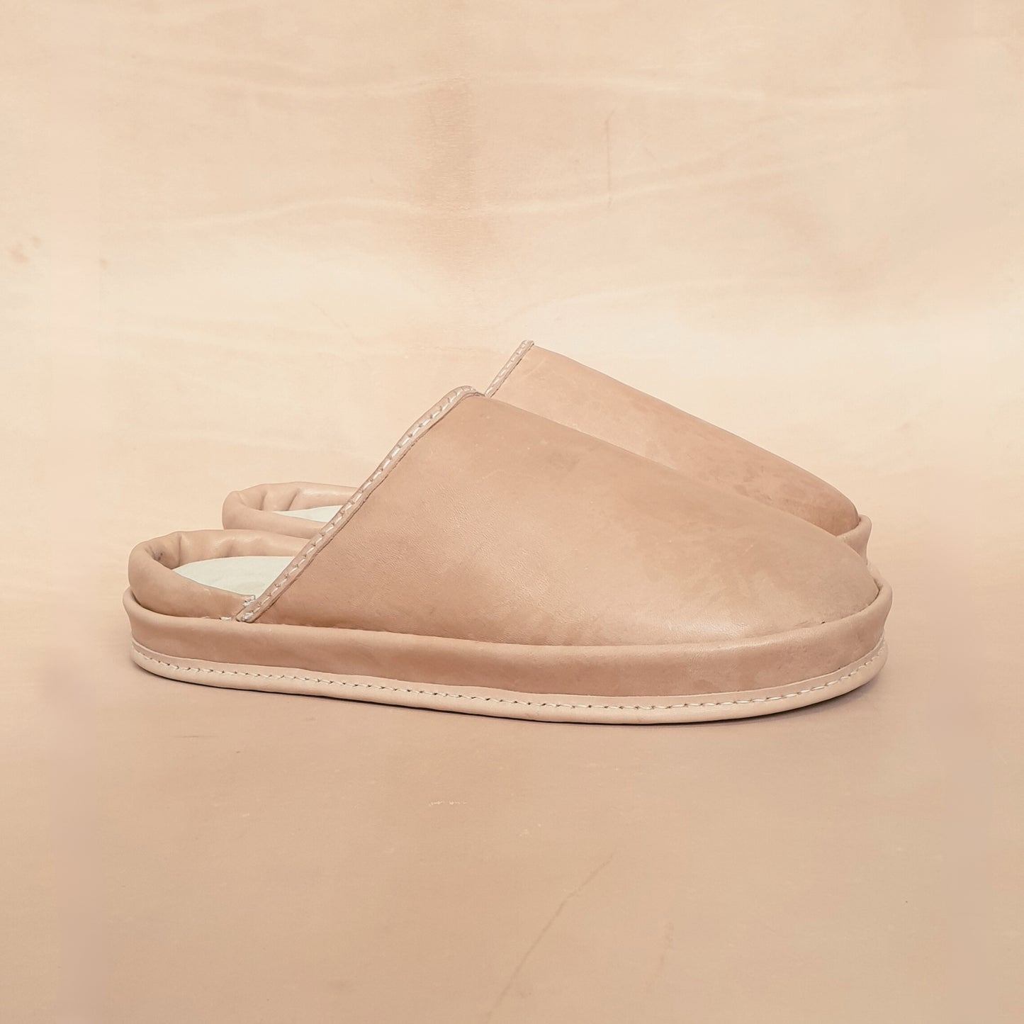 Beige leather slippers on a beige background