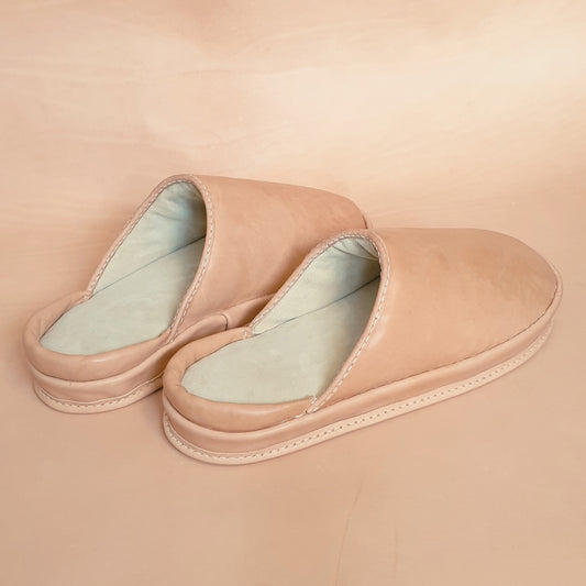 Pair of beige adaptive leather slippers on a beige background