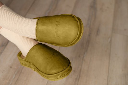 A person wearing Olive Earth leather clogs for a relaxed indoor look. These shoes are perfect for mindful living and comfort.