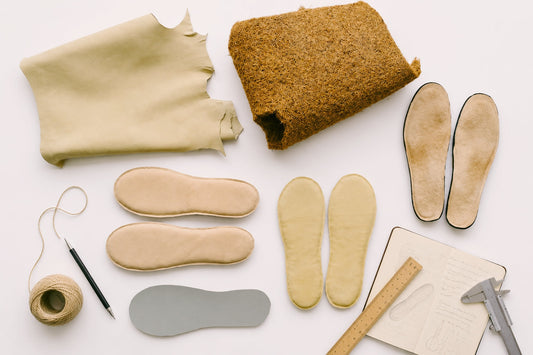 Flat lay of SPA·GAIT insole materials including natural leather, coconut fibre, cushioning base layers, and finished insoles used during long-term wear testing.