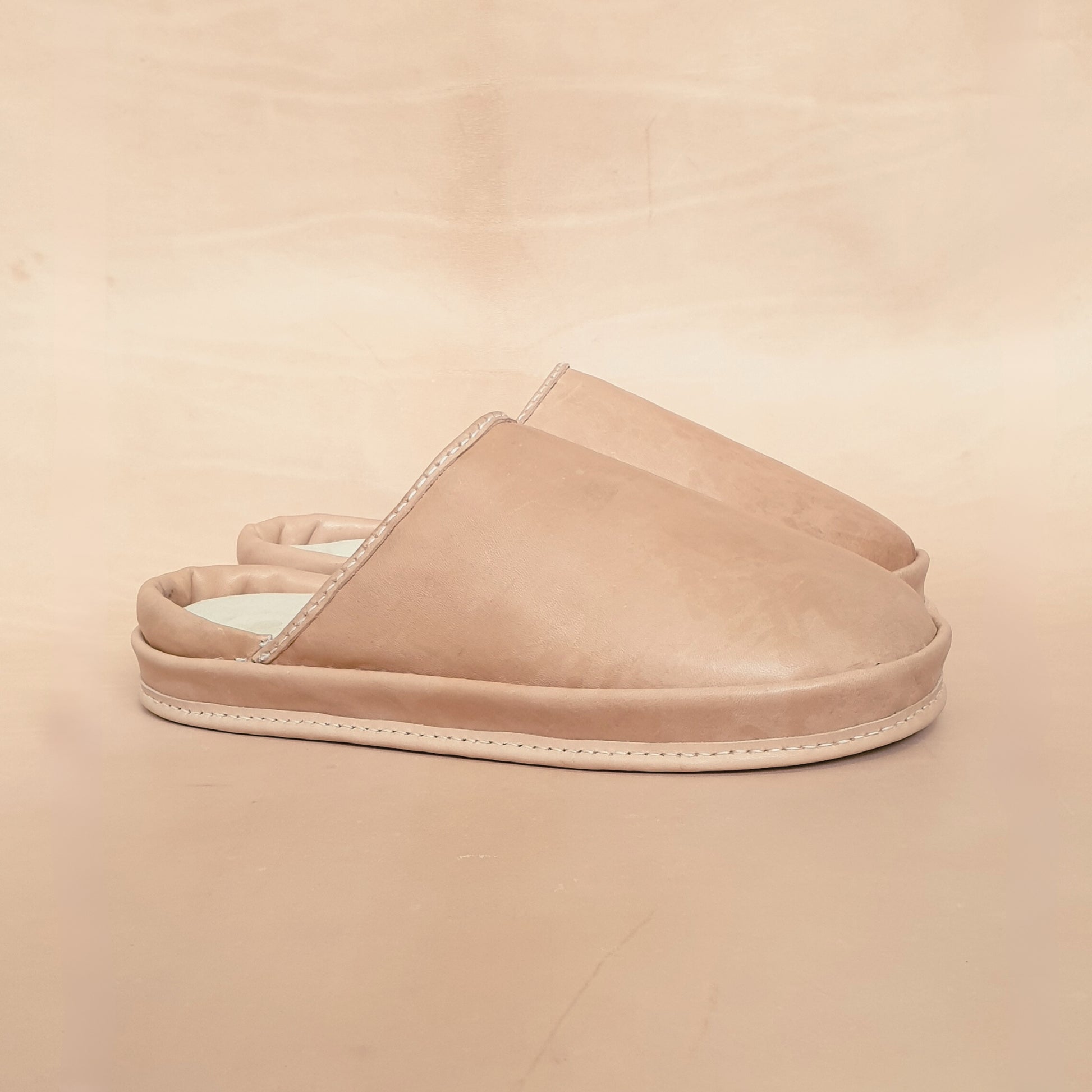 Beige leather slippers on a beige background