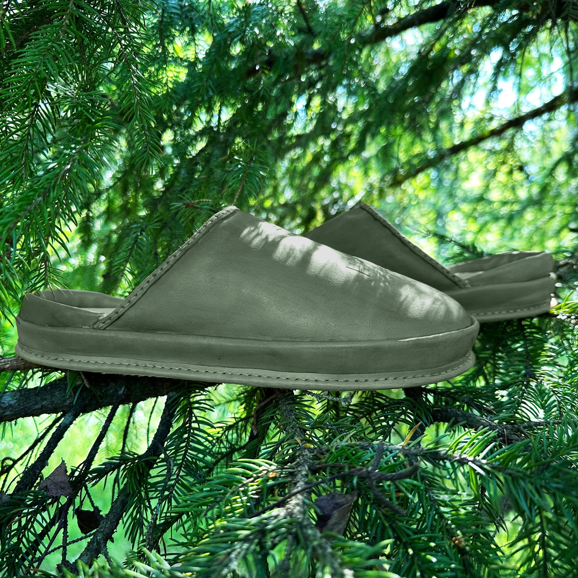 Moss Whisper leather clogs photographed on pine needles. These handmade art clogs are inspired by nature and made for comfort.