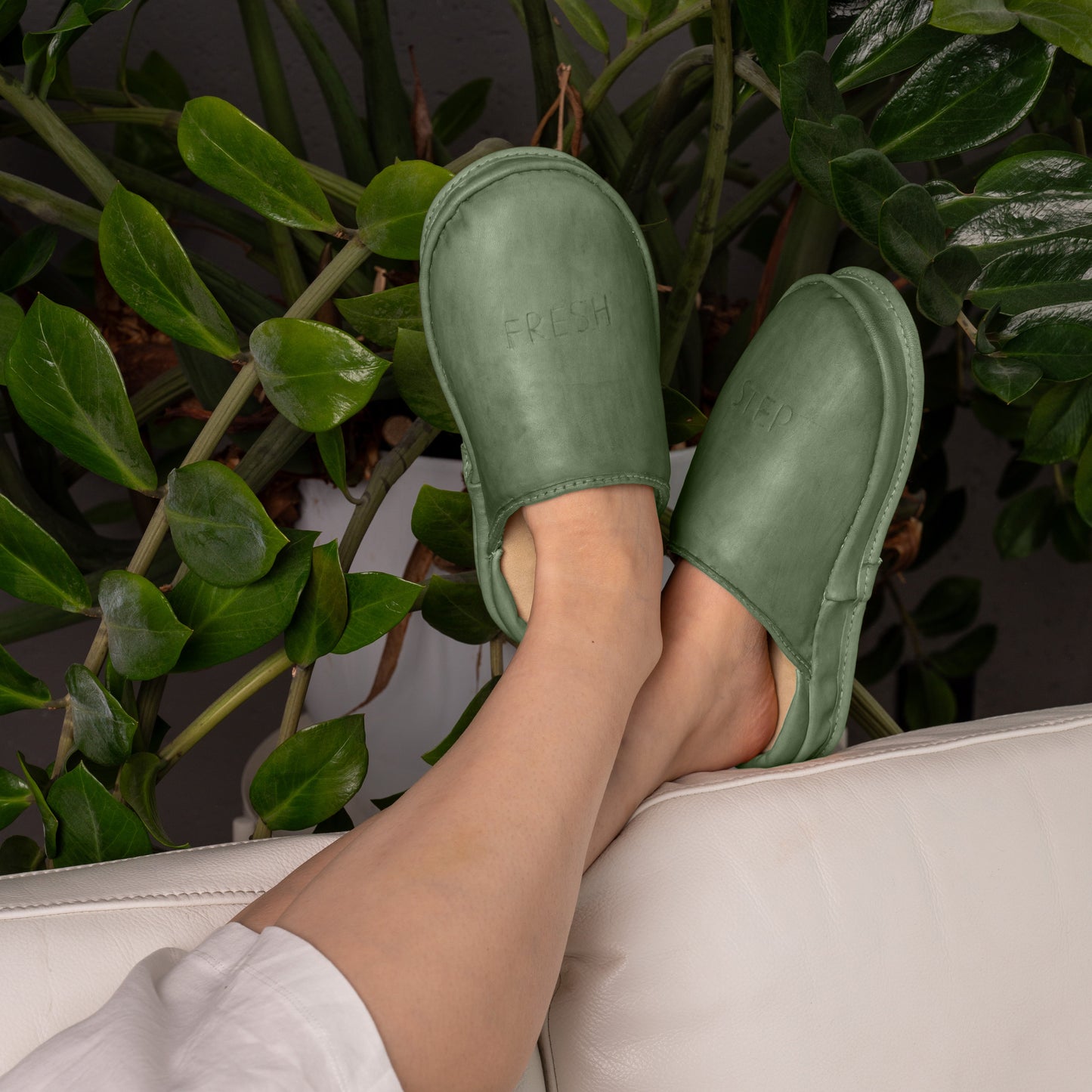 Forest Core leather slippers on a sofa. These comfortable leather shoes are designed for relaxation and coziness at home.