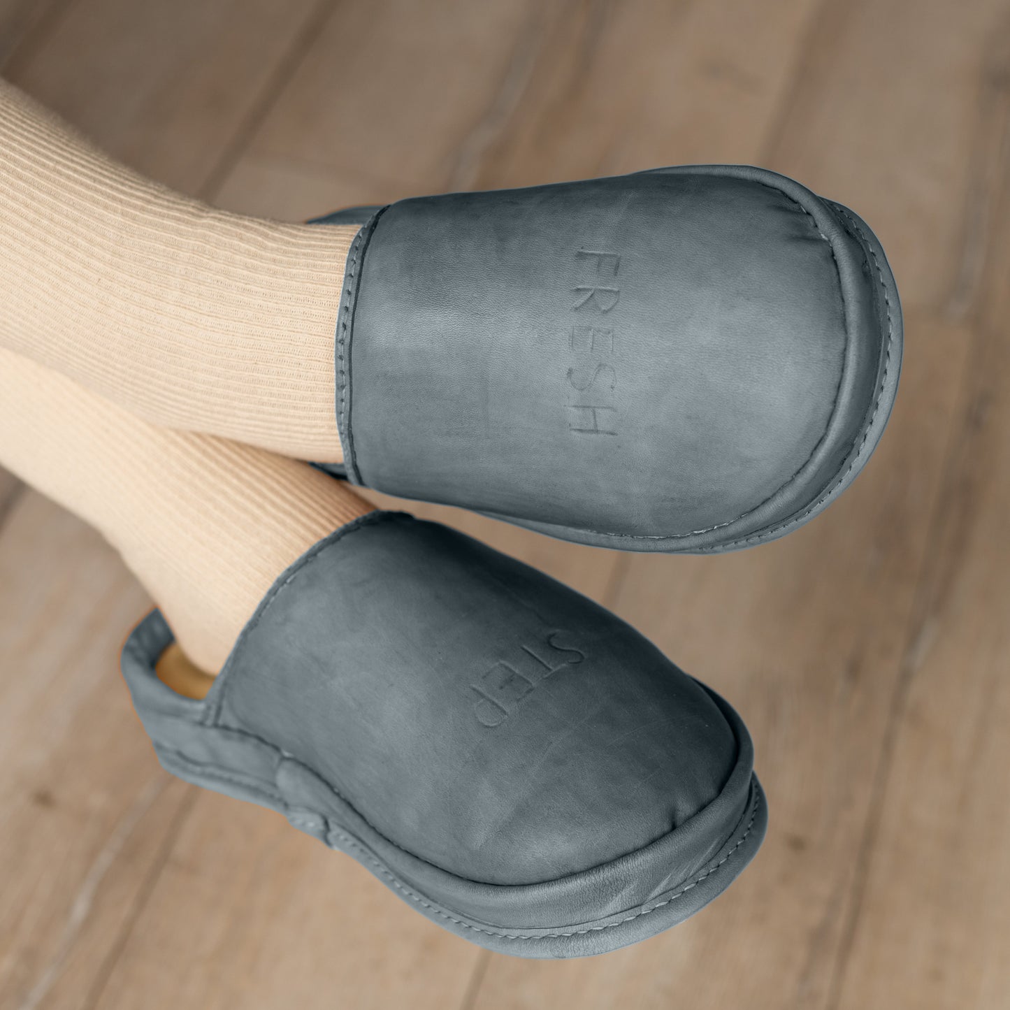 SPA GAIT Storm Ash brown leather clogs worn in minimalist interior. Comfortable leather slippers with anatomical fit and breathable structure.

