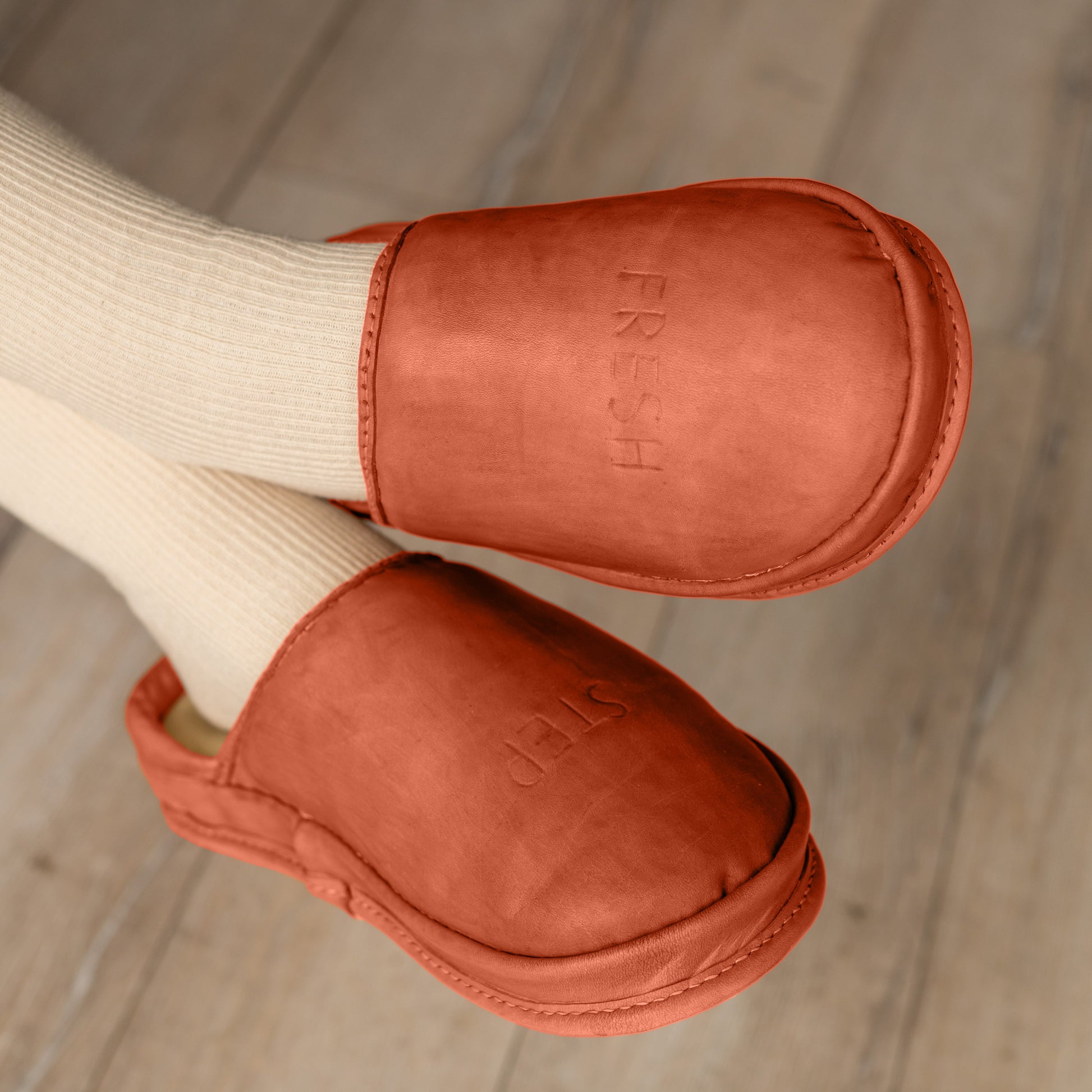 These Clay Flame leather clogs for women are worn on feet indoors, showcasing their comfortable and stylish design for everyday use.