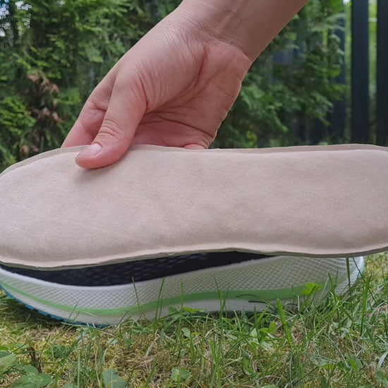 A person outdoors demonstrates the flexibility and smooth texture of the beige SPA GAIT Basic Leather insole. The video includes a quick step-by-step guide on inserting the insole into a black shoe, ending with a banner showing how it moulds to the foot after 10 hours of wear.